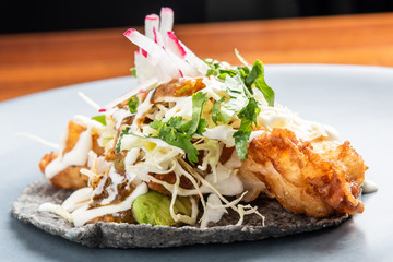Deep fried fish taco in a black corn torilla