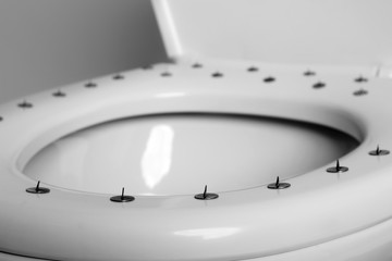 Toilet bowl with pins on white background, closeup. Hemorrhoids concept