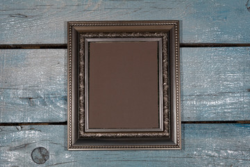 Background, texture. Close-up. On a painted plank background is a vertically silver picture frame with a brown middle.