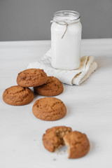 Milk in a glass jar and oatmeal cookies on a white table background. Copy, empty space for text