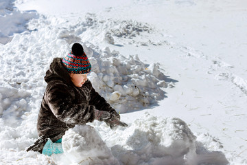 Fototapeta na wymiar Beautiful happy little kid play with snow in a country yard