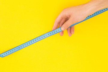 cropped view of man holding measuring tape isolated on yellow