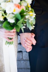 Obraz na płótnie Canvas Bride and groom holding hands with flowers