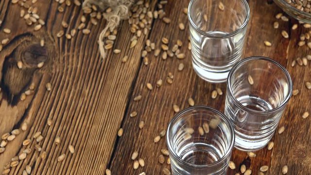 Pouring in a wheat liqueur shot on an old vintage looking table (4K UHD footage)