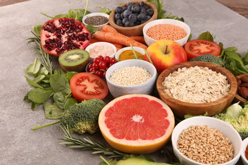 Healthy food clean eating selection: fruit, vegetable, seeds, superfood, cereals, leaf vegetable on rustic background