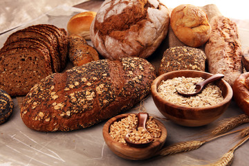 Assortment of baked bread and bread rolls and cutted bread on table background