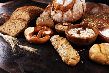 Assortment of baked bread and bread rolls and cutted bread on table background