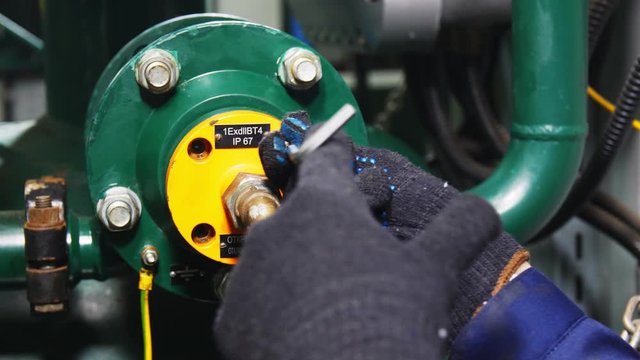 worker twists screws on skid at gas oil refinery plant