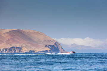 Boat at high speed carries tourists on an excursion to the Ballestas island, Region Ica, Peru. Copy past