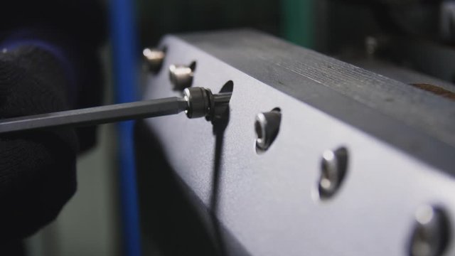 unscrewing screws on skid cabinet with screwdriver closeup