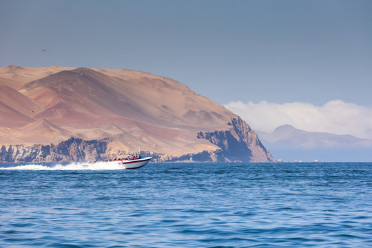 A speed boat carries tourists on an excursion to the island of Ballestas, the Ica region, Peru. Copy paste.