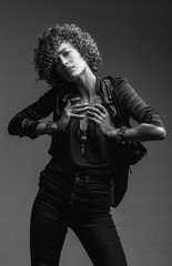 Obraz premium Young attractive sexy girl with curly hair in the form of a rock singer in a leather jacket. Black and white image