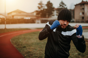 Fototapeta premium Handsome young man boxer practicing shadow boxing