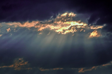 dark thunderclouds with cases of the sun. Rays of light against a background of dark blue clouds in the evening