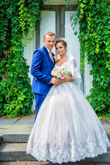 Beautiful sensual brunette bride and handsome groom. Newlyweds  old door embracing and posing kissing 