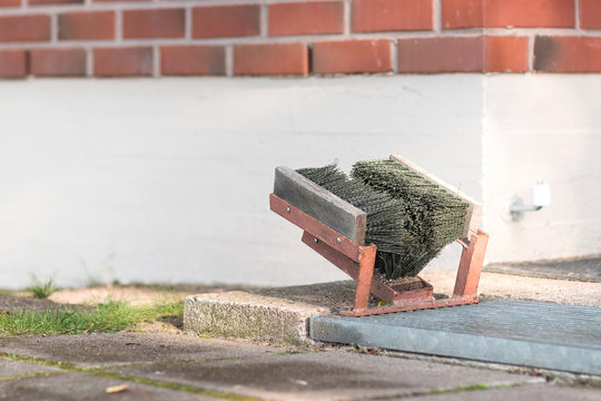 Street brush and boot scrabber for cleaning shoes from dirt and snow near the house.