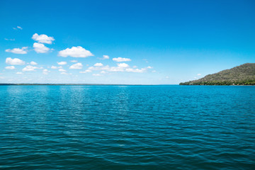 Lake Itza with cocodrile shaped mountain on sunny day, El Remate, Peten, Guatemala