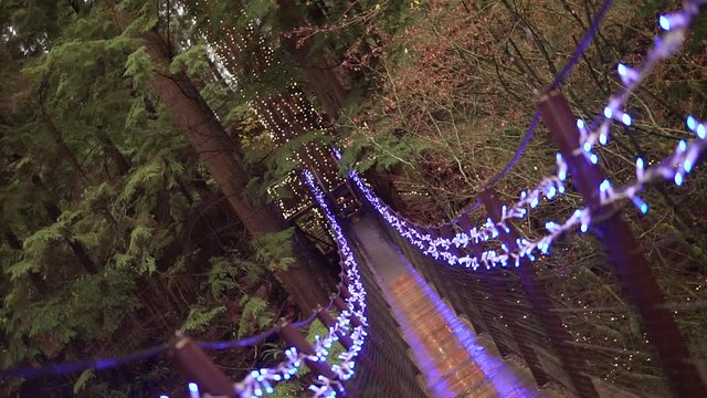 This was taken at a higher frame rate and has been converted to a slow motion video clip. Slow motion barrel shot of a suspension bridge covered in Christmas lights.