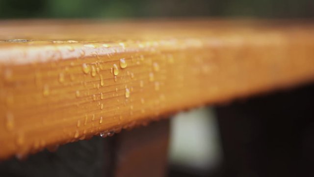This was taken at a higher frame rate and has been converted to a slow motion video clip. Macro footage of rain droplets on a picnic table.