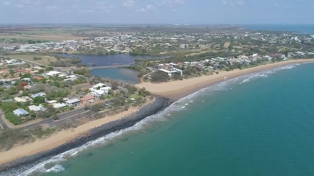Aerial, low lying coastal town and beach on sunny day, wide shot. Queensland, Australia