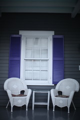 white wicker chairs on proch with purple shutters