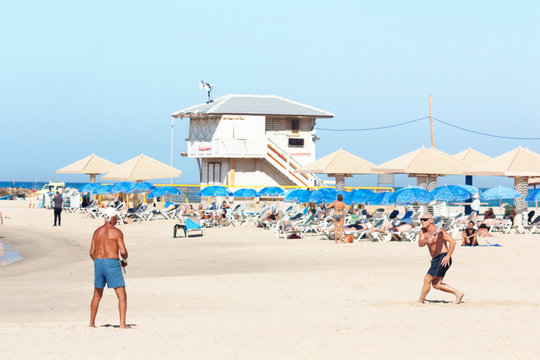 Two men play matkot on the beach