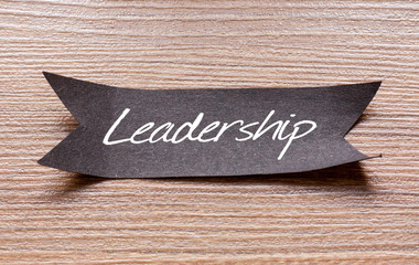 Leadership word written on Black papper with wooden background