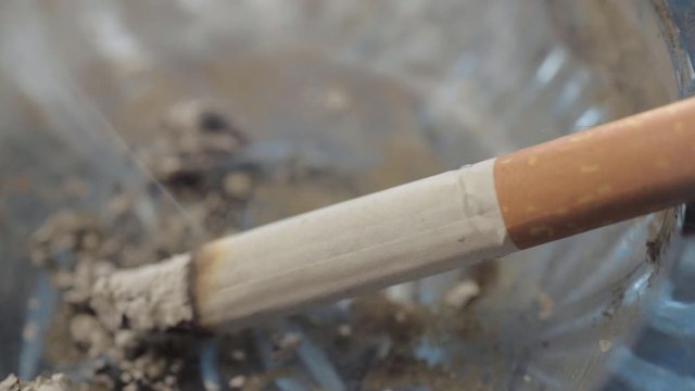 Lit cigarette smoking and burning away in an ashtray