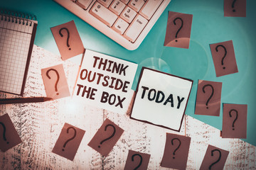 Conceptual hand writing showing Think Outside The Box. Concept meaning Be unique different ideas bring brainstorming Writing tools and scribbled paper on top of the wooden table