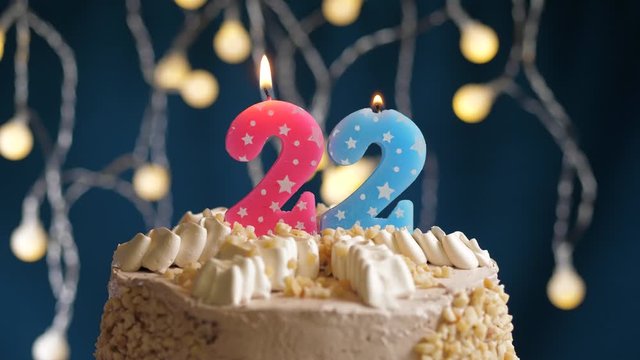 Birthday cake with 22 number pink candle on blue backgraund. Candles blow out. Slow motion and close-up view