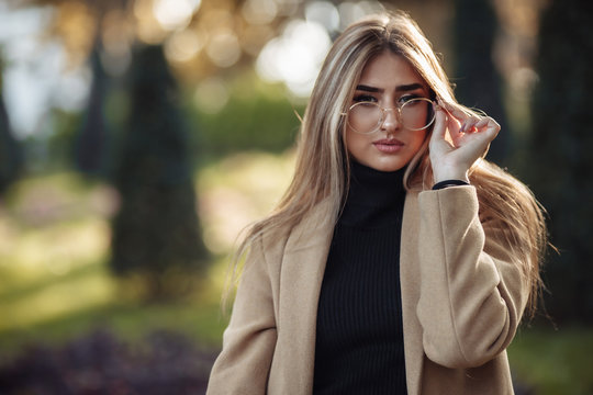 Autumn portrait. Stylish woman in image glasses and coat in the park