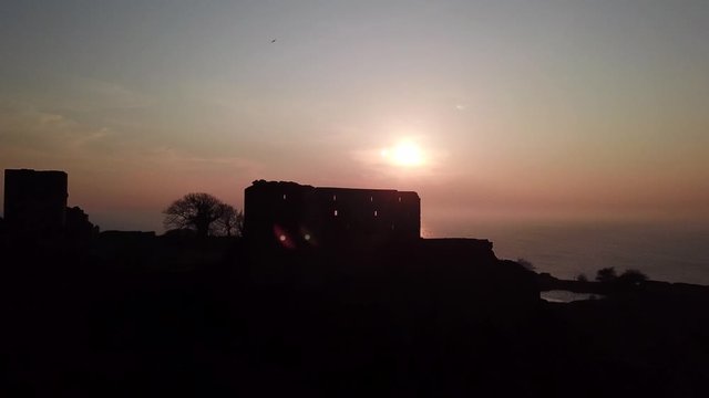 Stunning rising drone shot of a midieval fortification during glimmering sunset 