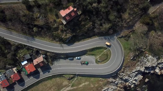 Miniature toy-like cars travel windy mountain road in picturesque rising shot from above