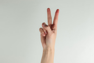 Female hand shows gesture v symbol on a white background