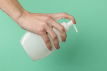 Minimalism beauty concept. Female hand hold a bottle of cream on blue background. Clean and soft skin. The concept of health and beauty. Studio shot