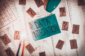 Handwriting text writing Data Integration. Conceptual photo involves combining data residing in different sources Writing tools, computer stuff and scribbled paper on top of wooden table