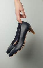 Studio fashion shot. Female hands holding classic high heel shoes on a white background