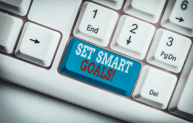 Text sign showing Set Smart Goals. Business photo text list to clarify your ideas focus efforts use time wisely White pc keyboard with empty note paper above white background key copy space