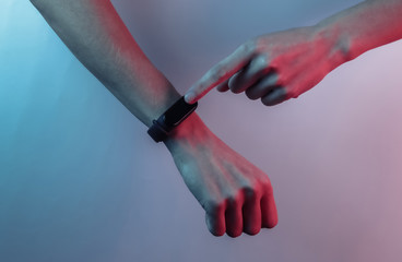 Female hand with a smart bracelet. Modern gadgets. Creative pop art pink blue neon color. Trendy gradient illumination. Night light
