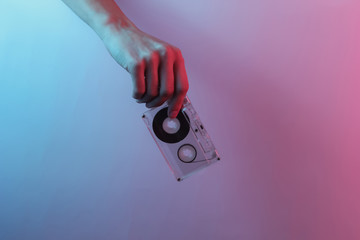 Retro wave 80s. Hand holding audio cassette. Creative pop art pink blue neon color. Trendy gradient illumination. Night light
