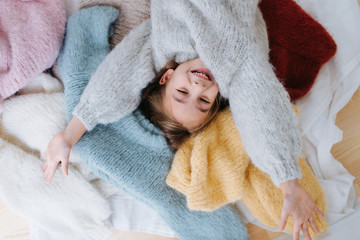 Happy smiling cute littlegirl is lying on a pile of soft fluffy multi-colored freshly washed...