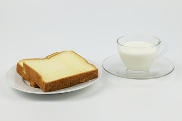 Sliced bread on white plate with  cup of milk on white background