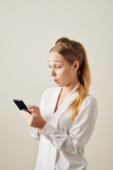 Shocked young woman reading text message with exciting news on smartphone