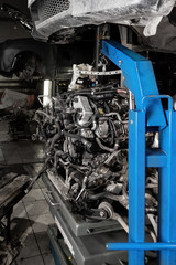 Used v8 engine with eight cylinders suspended mounted on a crane for overhaul repair and installation on a car after a breakdown in the vehicle workshop. Auto service industry. Сylinder scratches.