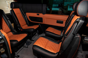 Four rear seats in a minibus are deployed to each other and tightened in black and brown leather...