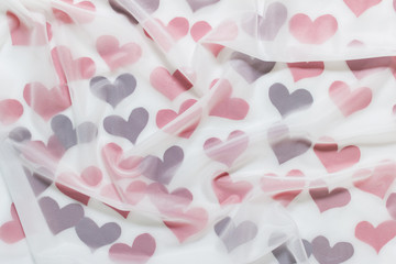 Abstract Valentines day celebration cheerful background with many red fabric hearts covered with transparent white cloth.