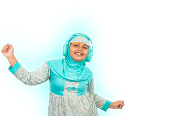 A young Asian girl wearing hijab listening to music on headphones dancing, smiling and looking at camera
