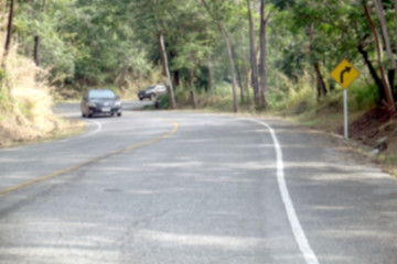 Asphalt road through the forest, blur natural background