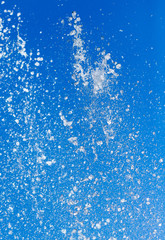 Splashing water from a fountain on a background of blue sky