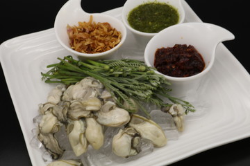 Fresh oyster with seafood sauce, chili paste and acacia on white plate